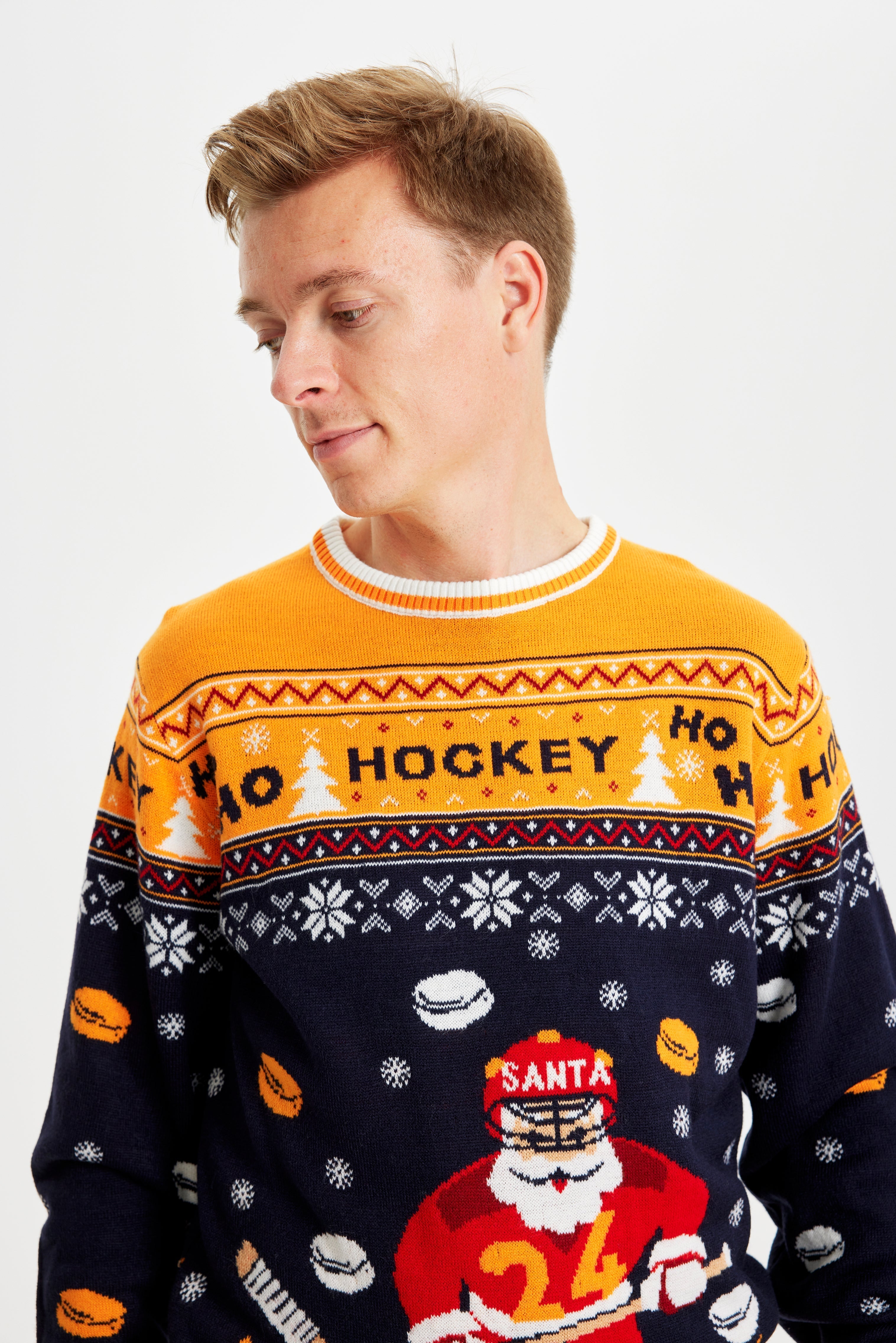 En man vänd åt sidan iklädd en jultröja med en tomte som spelar hockey.